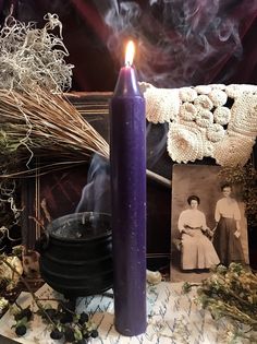 a purple candle sitting on top of a table next to an old photo and other items