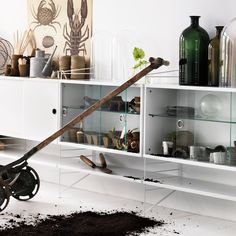 a wheelbarrow leaning against a wall filled with pots and vases on shelves