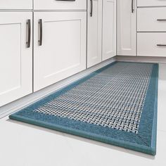 a kitchen with white cupboards and blue rug on the floor in front of cabinets