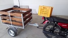 a red motorcycle parked next to a wooden crate on a cart attached to the back of a moped