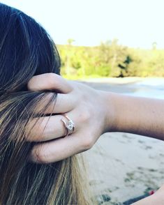 a woman with her hand on the back of her head, wearing a gold ring