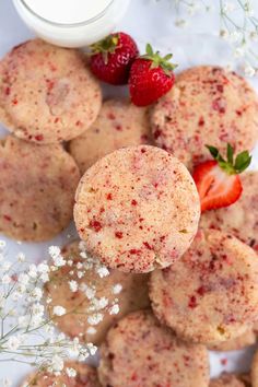 strawberries and cookies on a plate next to a glass of milk with some sprinkles