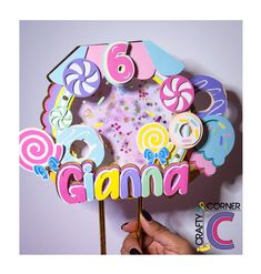 a person holding up a candy themed cake topper