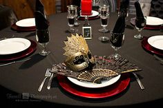 a black table with red plates and silverware on it is set for an elegant dinner