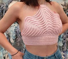 a woman wearing a pink crop top and jeans