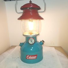 a blue and red lamp sitting on top of a table next to a white wall