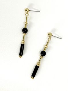 These long, dangle earrings feature polished onyx stone.  The geometric cut of the stone and brass elements creates a modern and minimalistic design while the variation in shapes adds detail and interest. The deep black of the onyx stone and the warm, metallic tone of the brass highlights the materials and creates contrast.  The earrings are finished with brass ball stud with stainless steel earring post.  Onyx is a semi precious gemstone known for its striking black color and smooth, glossy app Modern Black Drop Plug Earrings, Minimalist Black Linear Earrings For Gifts, Minimalist Black Linear Earrings As Gift, Minimalist Black Linear Drop Earrings, Minimalist Black Drop Earrings, Modern Black Long Drop Jewelry, Modern Gold Onyx Earrings, Modern Onyx Drop Earrings, Minimalist Black Brass Jewelry