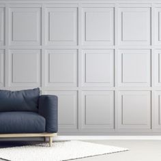 a blue couch sitting in front of a wall with white paneling on the walls