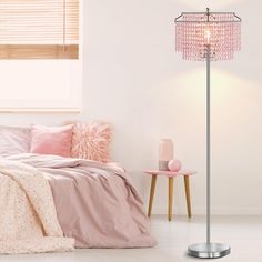 a bedroom with a bed, pink pillows and a floor lamp on the side table