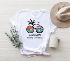 "Happiness Comes In Waves Shirt, Palm Tree Beach Shirt, Aloha T-Shirt, Florida Shirt, Miami Shirt, Tropical Shirt, Adventure Tee, Summer Tee ☀️☀️☀️☀️☀️ Everything in our shop is hand crafted and made to order. If you want different color or size contact me! If you would like something custom made to fit your personal style please message me and I will do everything to get you that something special. ---How To Order--- ⭐️Please, check and review all photos ⭐️Choose your t-shirt size and color ⭐️E Tropical T Shirts Women, Beach Tshirt Ideas, Tropical Tshirts, Vacation Cups, Miami Shirt, Happiness Comes In Waves, Florida Shirt, Palm Tree Beach, T-shirt Print Design