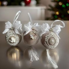 three ornaments are sitting on a table near a christmas tree