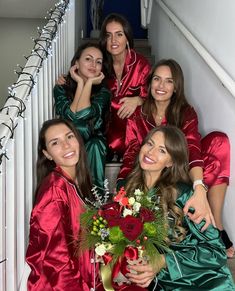 the bridesmaids are all dressed in red and green robes, posing on the stairs