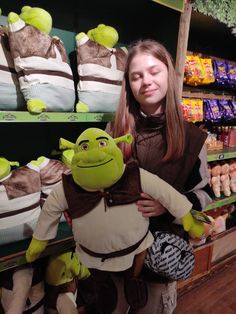 a girl is holding a stuffed toy in front of shelves