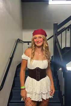 a woman in a white dress and red bandana is standing on the stairs with her legs crossed