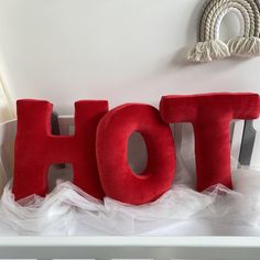 the word hot spelled out in red on top of a crib with white tulle