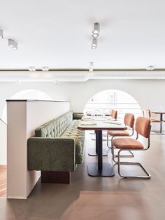 a long table with four chairs and a bench next to it in a large room