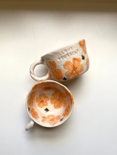 two orange and white coffee cups sitting next to each other