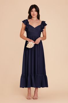 a woman wearing a navy blue dress with ruffles on the shoulders and shoulder