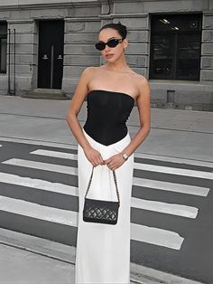 a woman in black and white is standing on the street