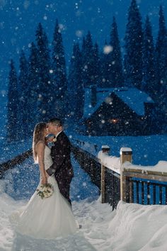 a bride and groom kissing in the snow at their winter wedding ceremony on a deck