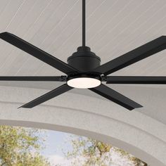 a black ceiling fan mounted on the side of a white roof over a patio area