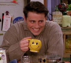 a man holding a yellow smiley face mug