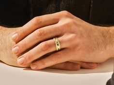 a close up of a person's hand with a gold ring on it,