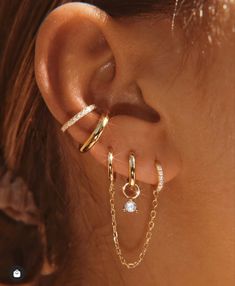 a close up of a person's ear with two gold chains attached to it