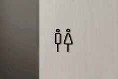 two black stickers on the side of a white wall with one person standing next to another