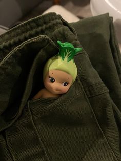 a small figurine sitting in the pocket of a pair of green sweatpants