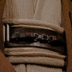 a belt is attached to the waist of a person wearing a brown coat and tan sweater