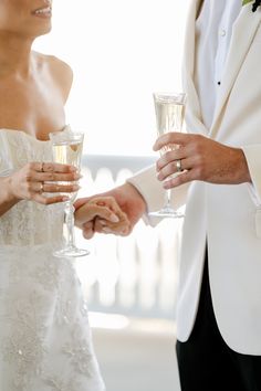 the bride and groom are holding champagne glasses in their hands as they hold each other's hand