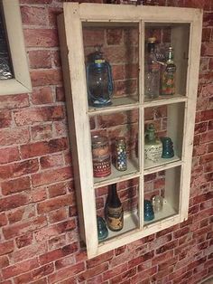 an old window is filled with glass bottles on the shelf in front of a brick wall