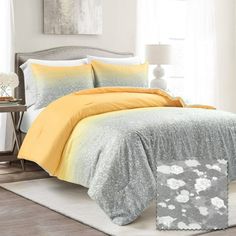 a bed with yellow and gray comforters in a bedroom next to a white rug