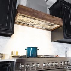 a stove top oven sitting inside of a kitchen next to black cupboards and drawers