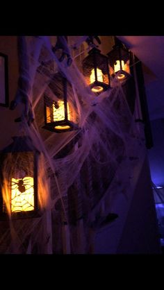 halloween decorations hanging from the ceiling with spider webs and lanterns on it's sides