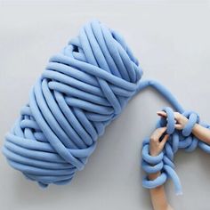 a hand holding a blue rope on top of a white table