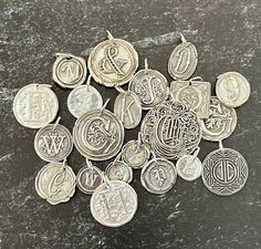 a pile of silver colored metal coins on a table with some writing and symbols in them