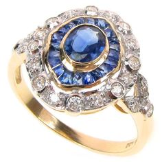 This BEAUTIFUL Art-Deco Inspired ring has been crafted from 9ct Solid Gold. A NATURAL oval cut Sapphire is the centrestone with gorgeous channel set and calibre cut Sapphires surrounding the entire ring. GENUINE earth mined round diamonds are bezel set in a frame with smaller claw set round diamonds. On each of the shoulders lies a beautiful leaf pattern inset with diamonds which adds additional appeal to this exquisite Art-Deco style ring. THIS VINTAGE INSPIRED ART-DECO SAPPHIRE & DIAMOND RING Yellow Gold Cluster Rings Hallmarked, Cluster Yellow Gold Hallmarked Rings, Yellow Gold Cluster Ring With Hallmark, Victorian Yellow Gold Cluster Rings, Collectible Yellow Gold Rings With Halo Setting, Heirloom Yellow Gold Sapphire Ring With Halo Setting, Victorian Cluster Yellow Gold Rings, Heirloom Round Cluster Ring, Vintage Yellow Gold Sapphire Ring With Halo Setting