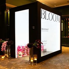 flowers and candles sit on the floor in front of a large sign that reads bloom