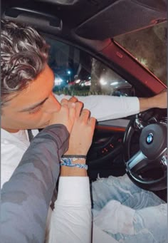 a man sitting in the driver's seat of a car with his hands clasped