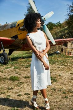 a woman standing in front of an airplane with her hands on her hips and looking off to the side