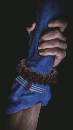 a person holding onto a blue object in their left hand and wearing a bracelet on the other