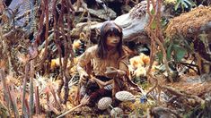 a doll is sitting on the ground surrounded by plants and other things that look like mushrooms