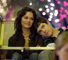 two people sitting next to each other in front of fireworks and lights on the night sky