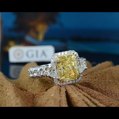 a fancy yellow diamond ring sitting on top of a cloth