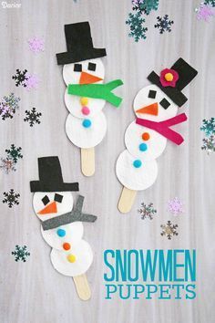 three snowmen popsicles made out of paper on a table with snowflakes