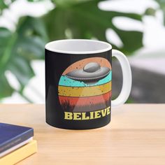 a black and white coffee mug sitting on top of a table next to a book