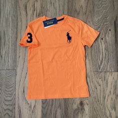 Polo By Ralph Lauren Orange Short Sleeve Shirt With Navy Blue Polo Insignia And 3 On Right Sleeve. 100% Cotton. Machine Wash And Dry. Size 7 Orange Cotton Polo Shirt For Summer, Summer Orange Cotton Polo Shirt, Orange Cotton Short Sleeve Polo Shirt, Basic Orange Short Sleeve Shirt, Toddler Tees Boy, Polo Ralph Lauren Kids, Tiger Shirt, Black Polo Shirt, Ralph Lauren Logo