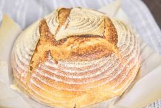 a loaf of bread sitting on top of a piece of wax paper in a basket